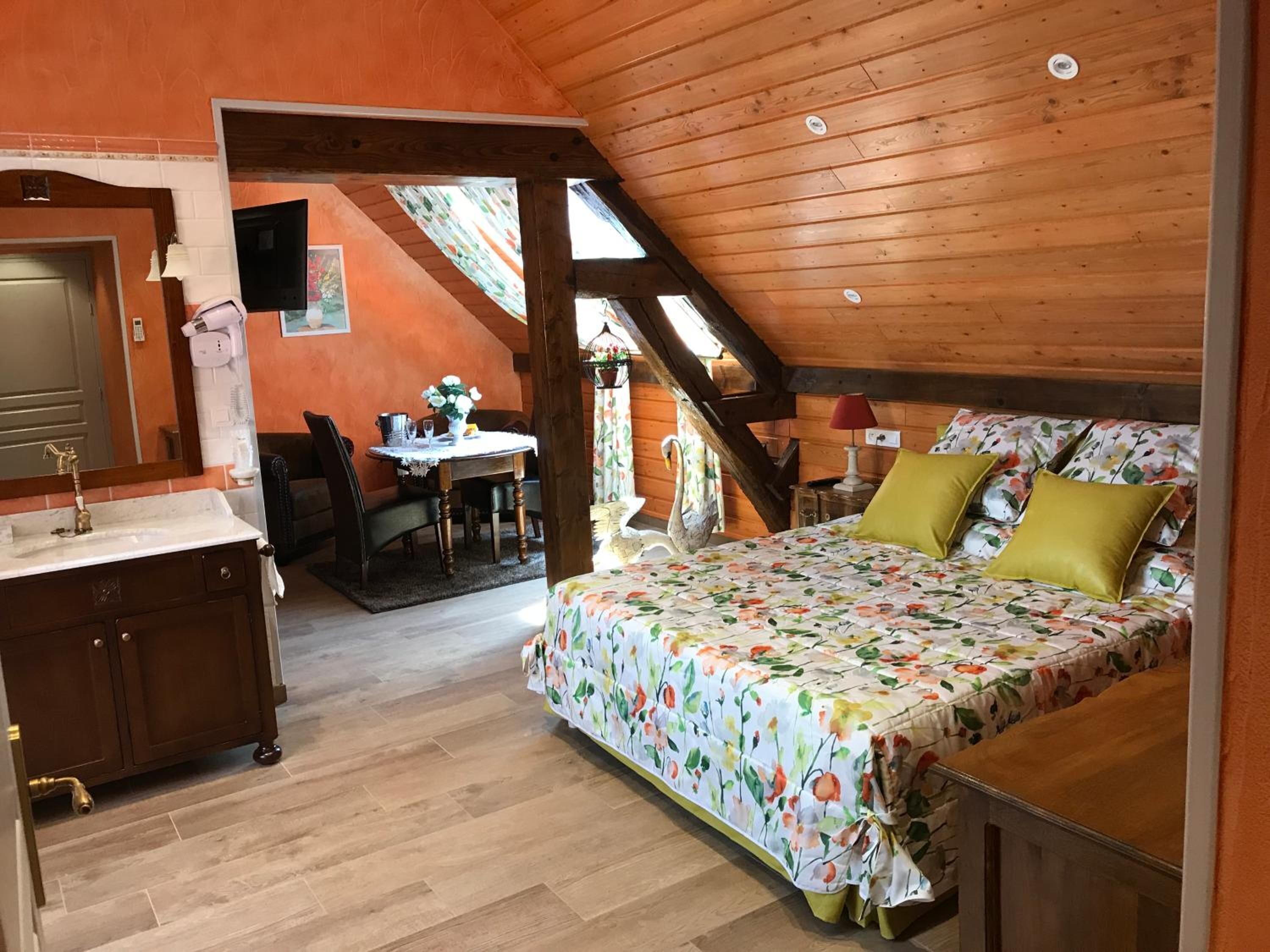 Een slaapkamer met een houten plafond, een bed met bloemenbedrukking, een nachtkastje en een raam met uitzicht op het landschap.