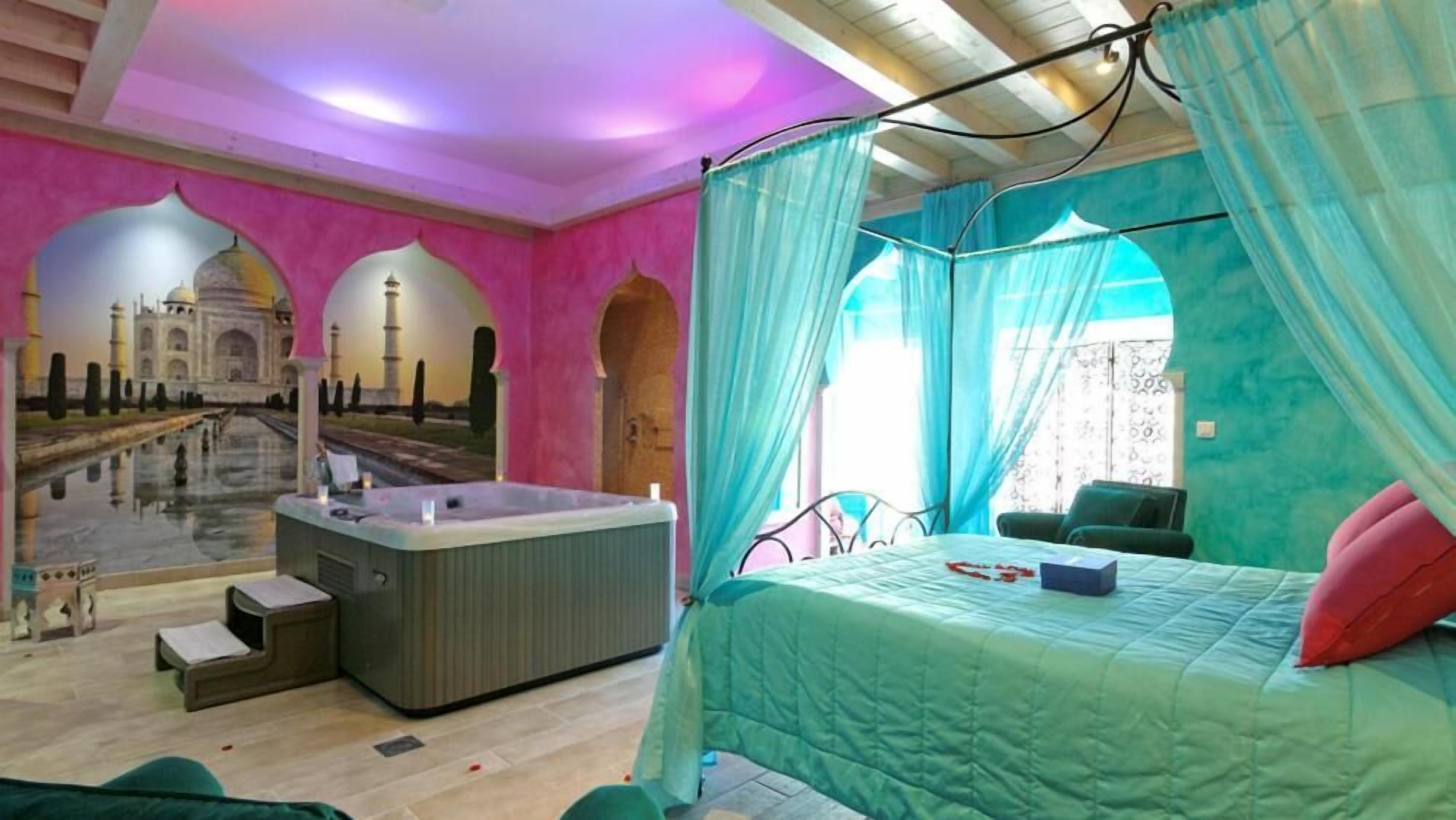 Een kamer met een bed, een bubbelbad en uitzicht op de Taj Mahal.