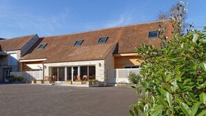 A building with a sloped roof, large windows, and a covered patio area with outdoor seating. - La Ferme Briarde (Augers-en-Brie)