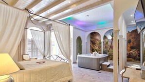 A spacious bedroom with a large bed, a sitting area, a hot tub, and a TV. - La Ferme Briarde (Augers-en-Brie)