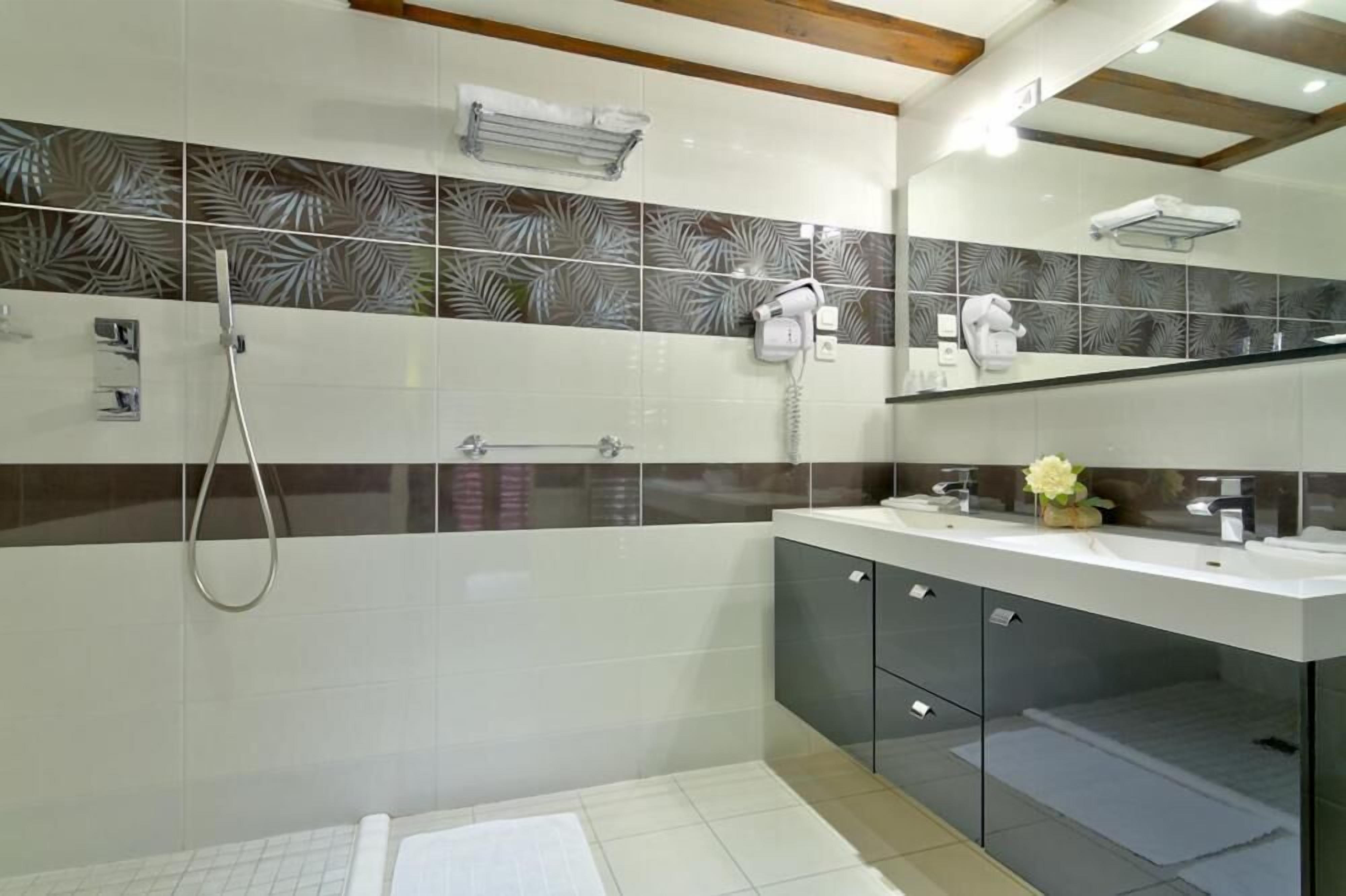 A modern bathroom with a shower, a vanity with a mirror, and a towel rack.
