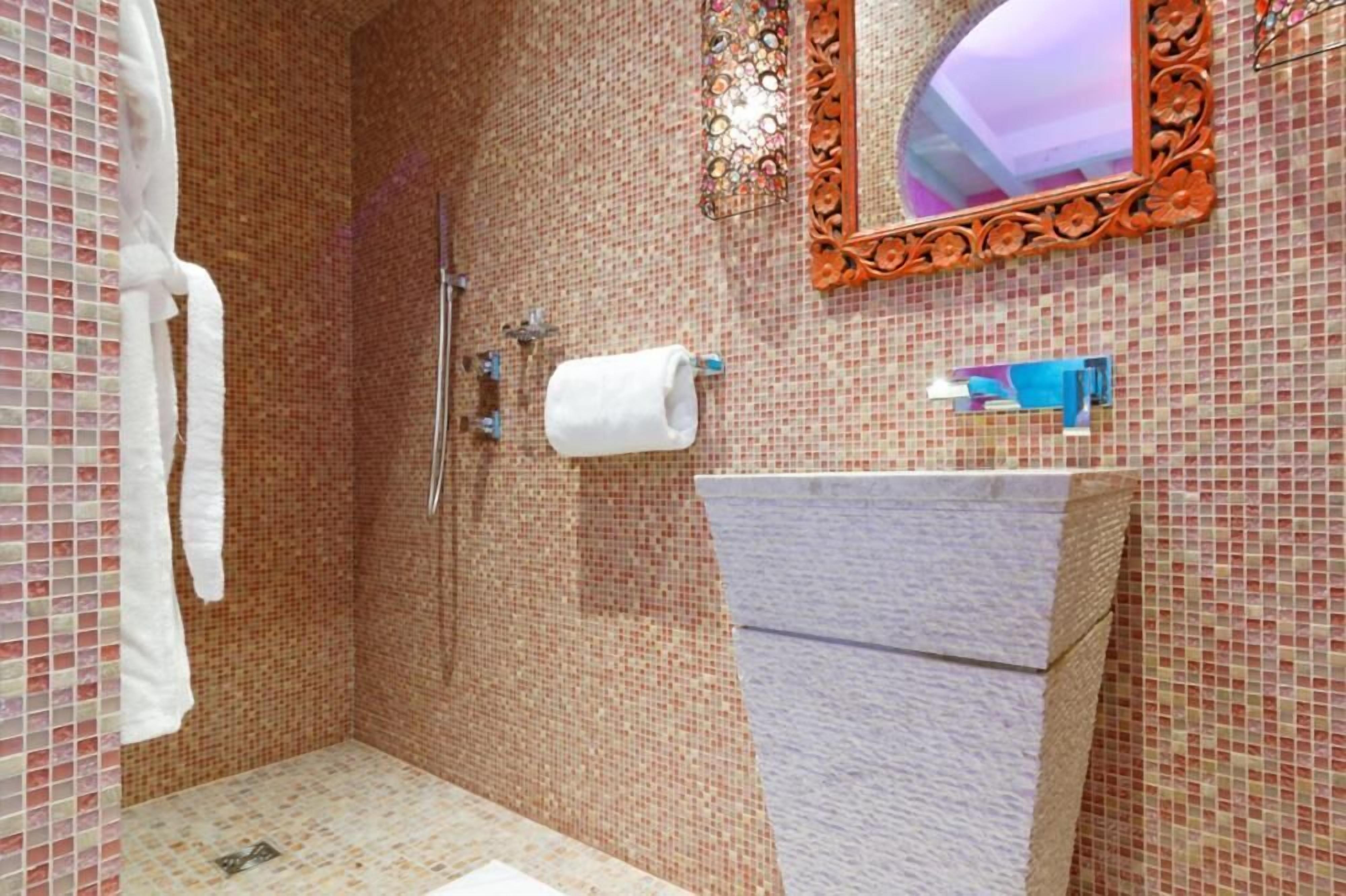 Ein Badezimmer mit Dusche, Waschbecken und Spiegel.
