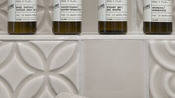 Cuatro botellas de loción corporal Santal 33 sobre una estantería.