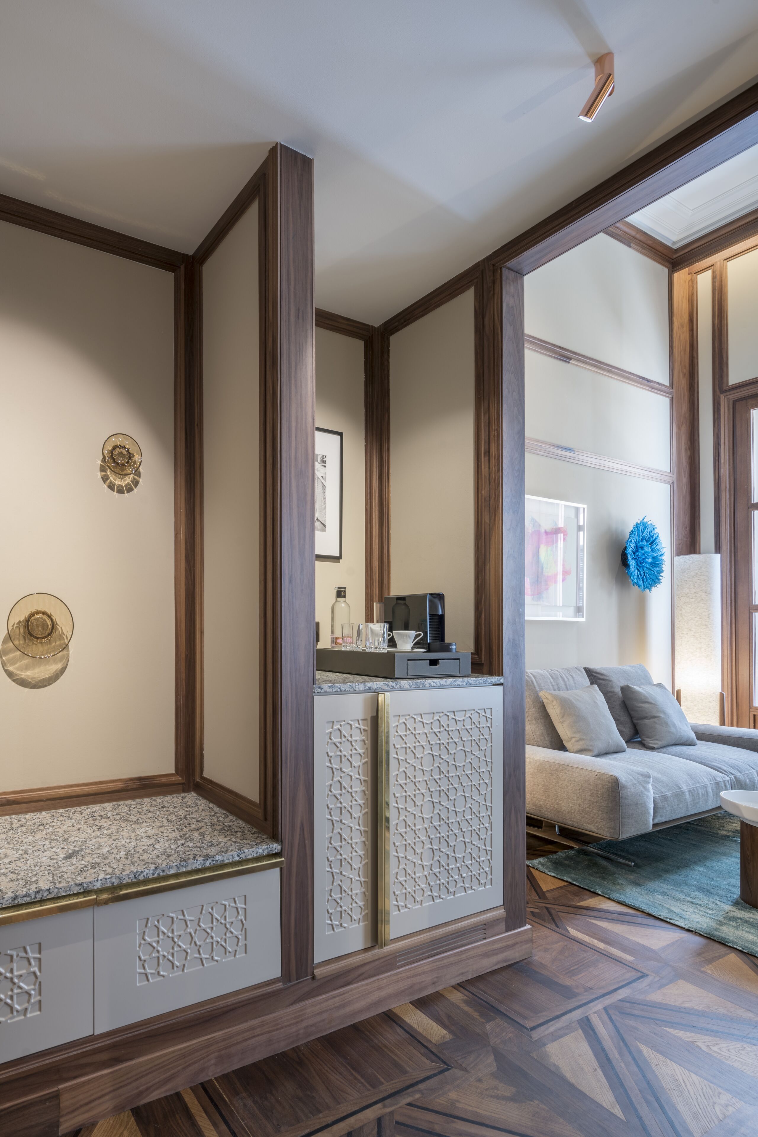 A room with a wooden partition, a sofa, and a coffee machine on a counter.