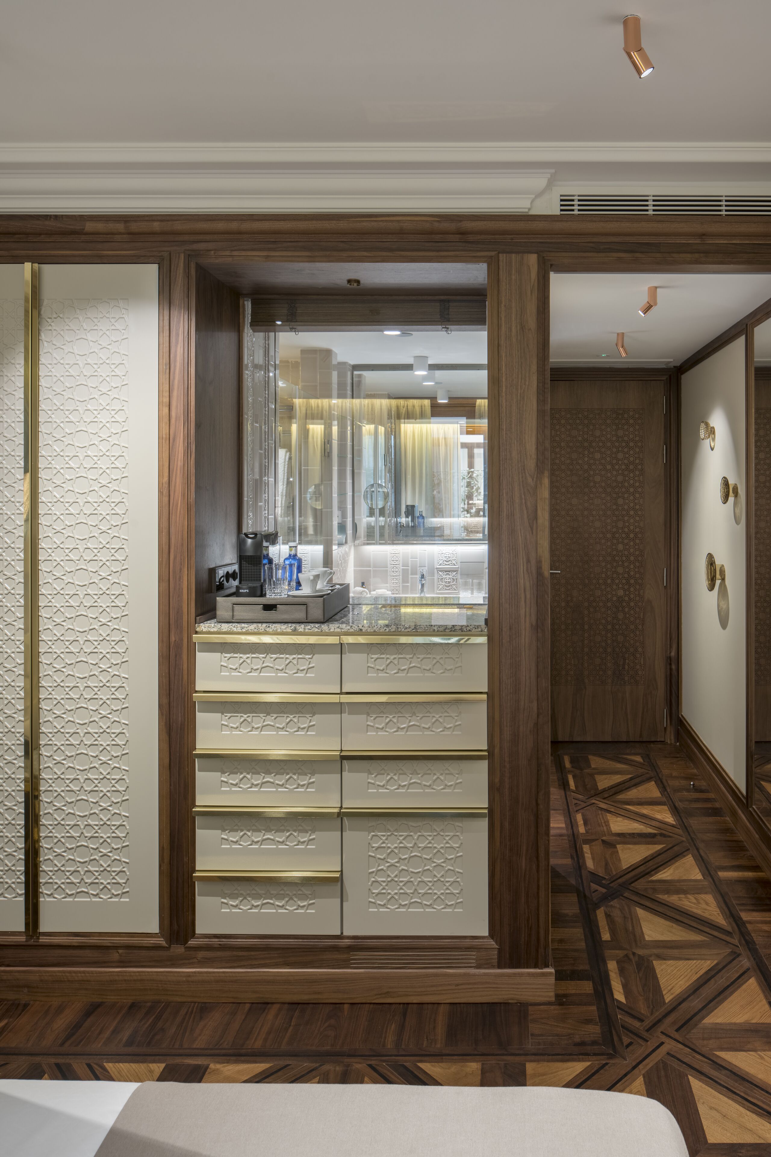 Une chambre d’hôtel avec un plancher en bois, un grand miroir et un mini-bar.