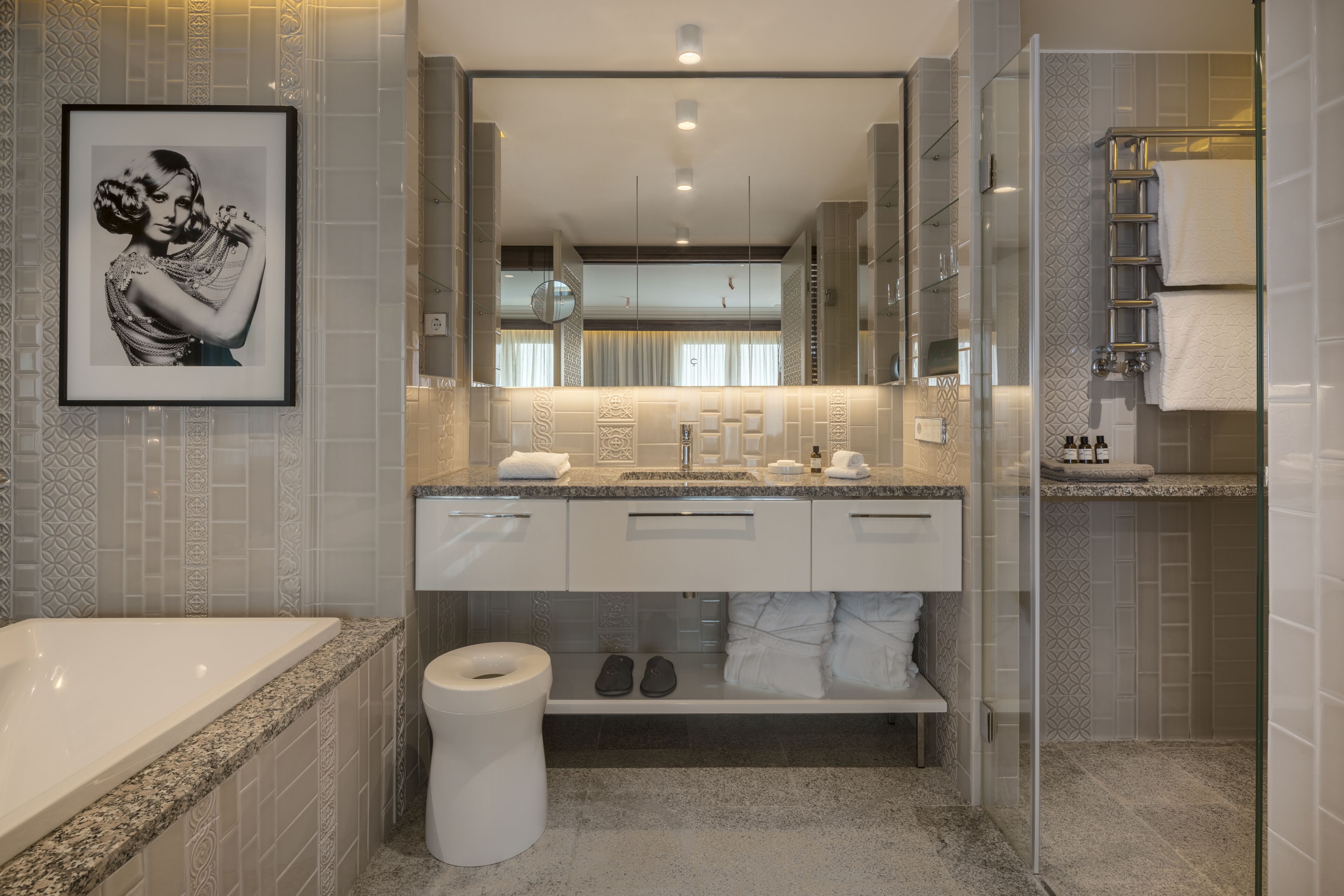 A modern bathroom with a large mirror, a bathtub, a toilet, and a shower area.