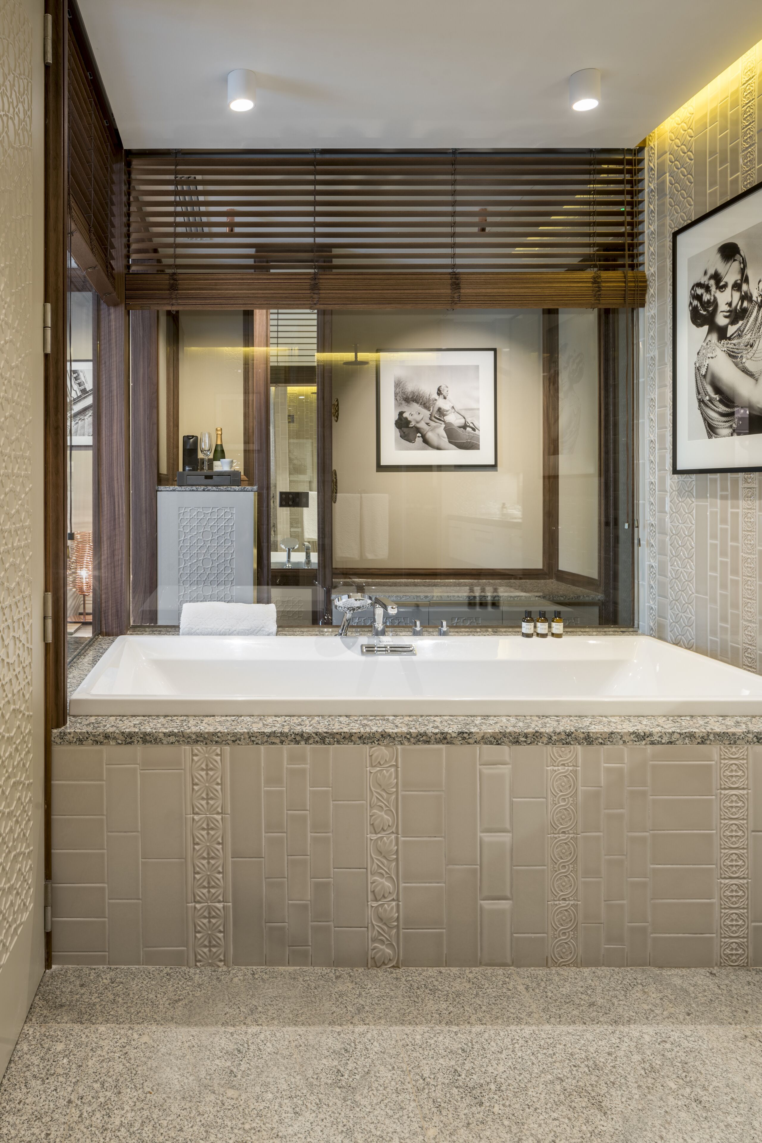 A modern bathroom with a large bathtub, a mirror, and a framed picture on the wall.