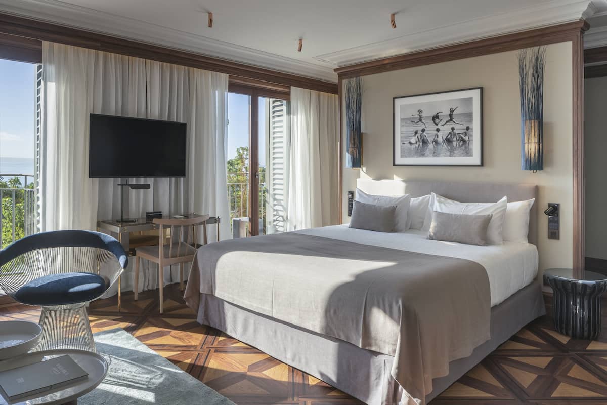 A hotel room with a large bed, a flat-screen TV, a dining table, and a chair.