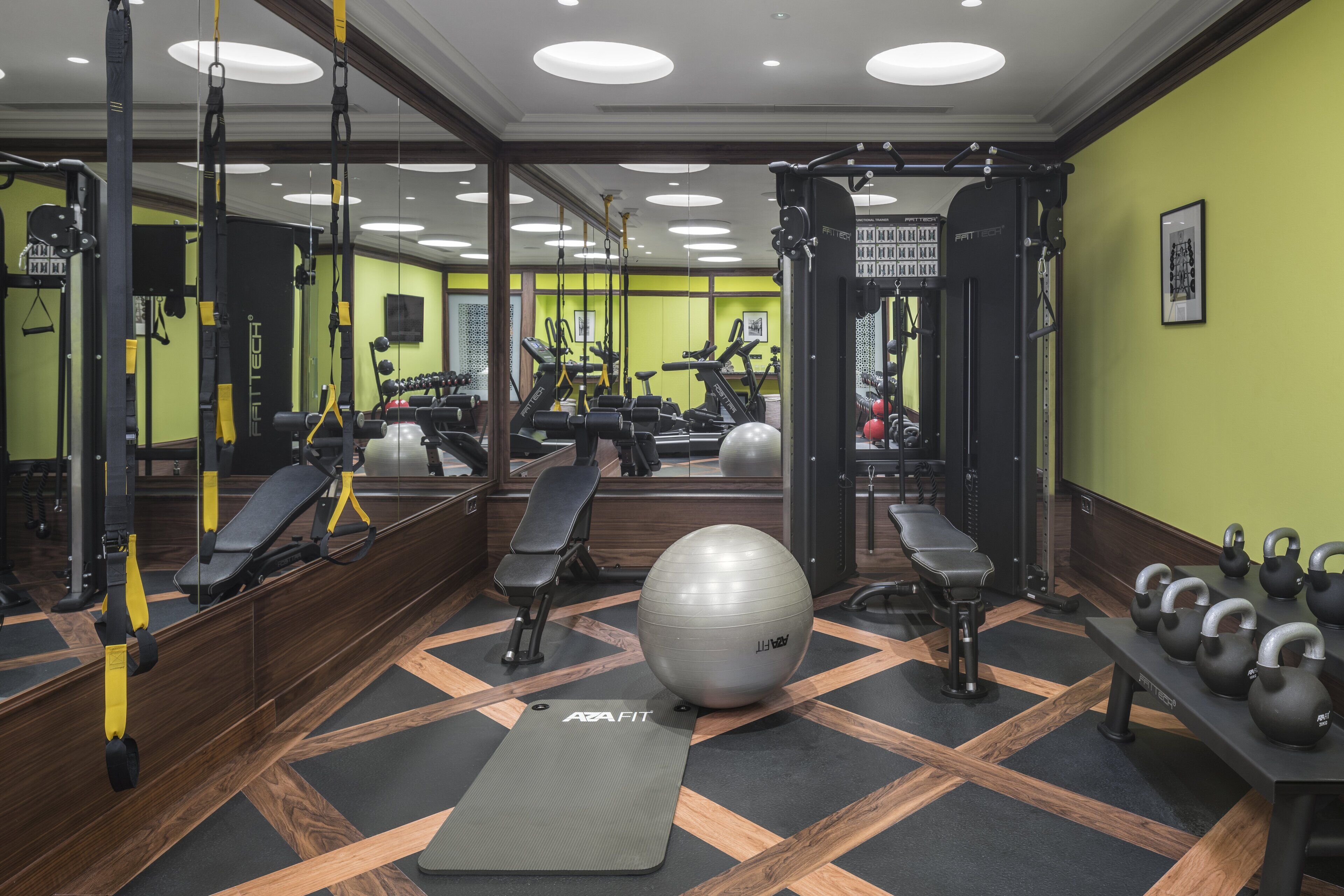 Une salle de sport équipée de matériel d’exercice, de bancs et d’un grand ballon de gymnastique.