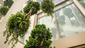 A modern building with multiple floors, large windows, and hanging plants. - Hotel El Llorenç Parc de la Mar - Adults Only (Palma de Mallorca)