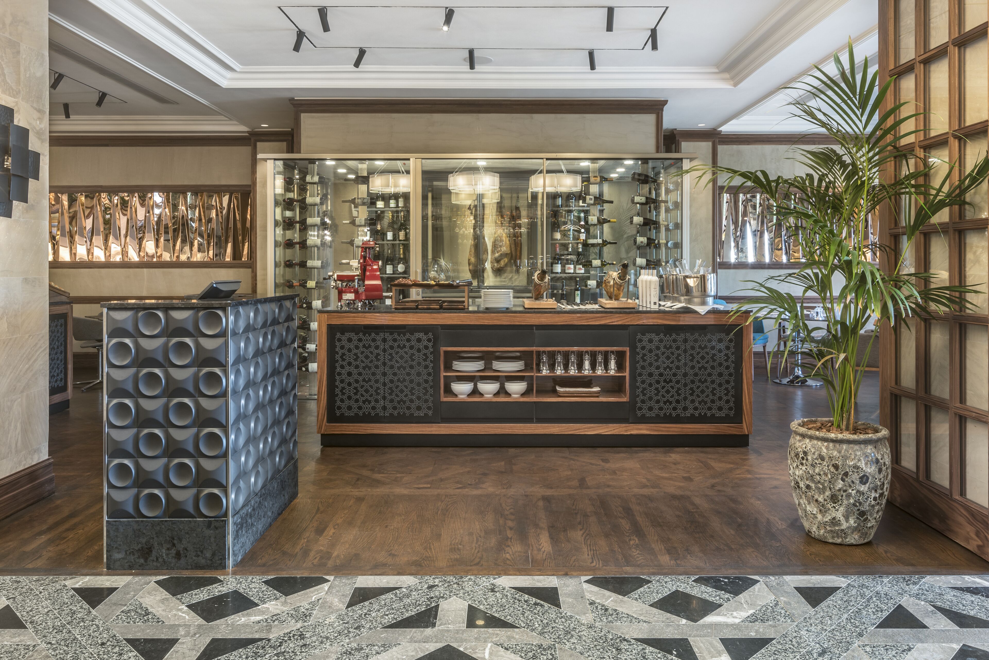 A reception area with a modern design, featuring a counter, seating area, and a large potted plant.