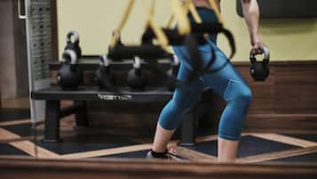 Ein Fitnessraum mit Trainingsgeräten, darunter Kettlebells und Widerstandsbändern.