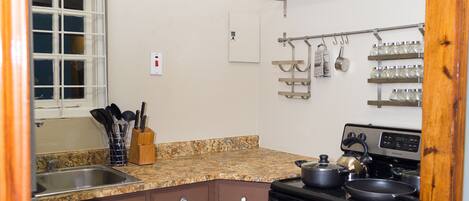 A kitchen with brown cabinets, a granite countertop, a stainless steel stove, and a window with a view.