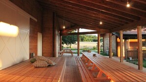 An open wooden deck with picnic tables and benches, a wooden ceiling, and a view of a field. - Evolution Wood Accommodation (Sant'Ippolito)