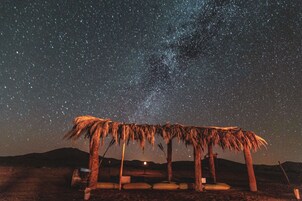 Una construcción con techo de paja bajo un cielo estrellado.