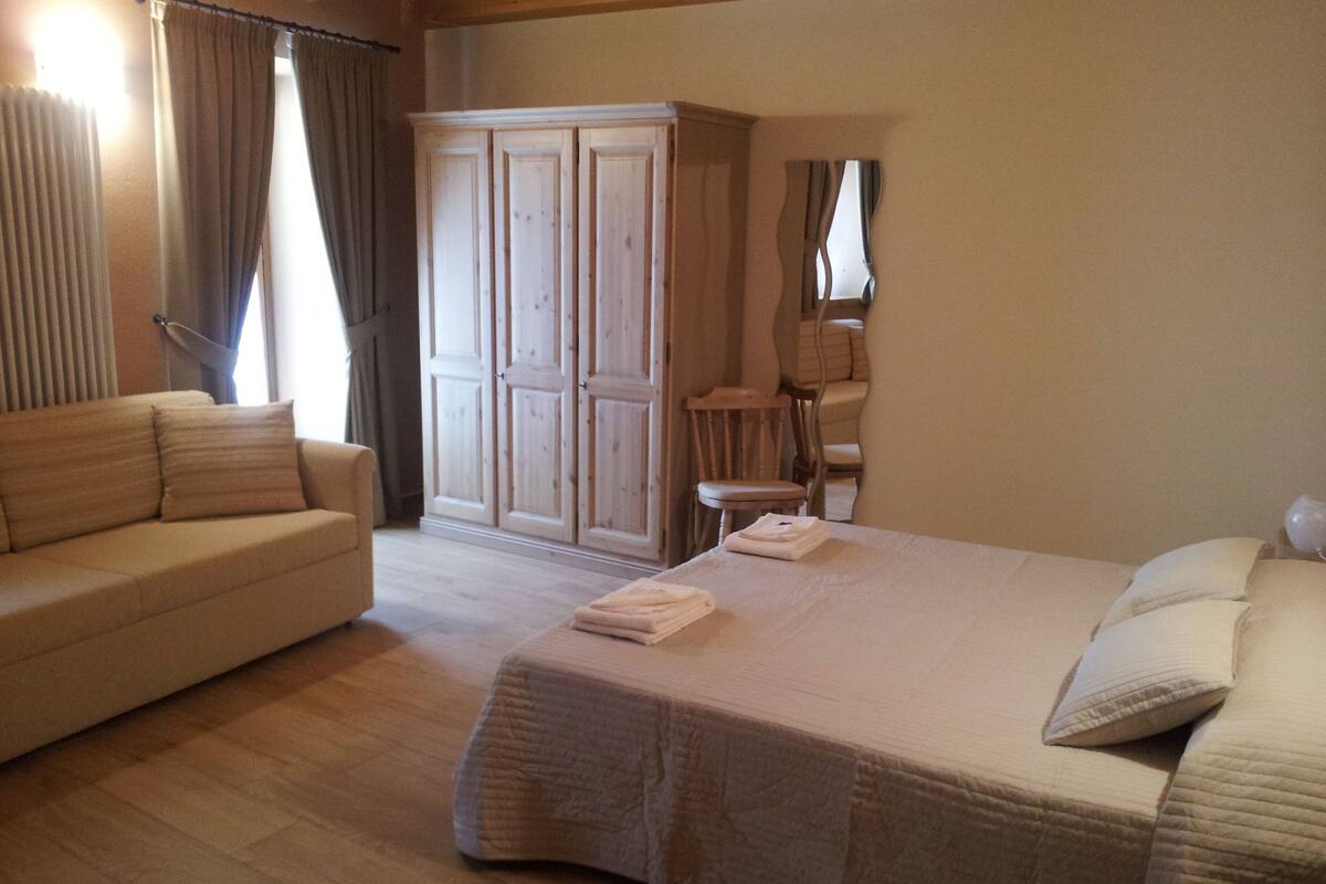 Une chambre à coucher avec un lit, un canapé, une armoire et une chaise.
