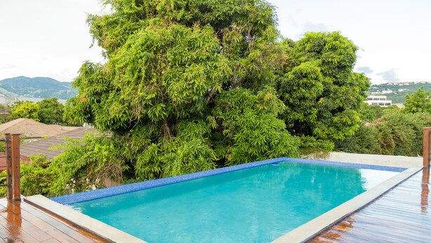 A rectangular swimming pool with a tiled edge, surrounded by a wooden deck. - Executive Suites at The Bromptons (Kingston)