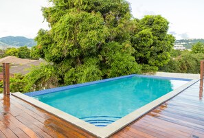 Ein rechteckiger Pool mit Fliesenrand, umgeben von einer Holzterrasse.