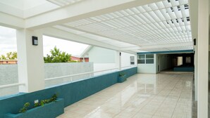 A spacious corridor with a tiled floor, blue walls, and a white ceiling with a grid pattern. - Executive Suites at The Bromptons (Kingston)