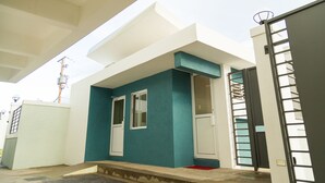 A modern building with a teal exterior, white doors, and a gated entrance. - Executive Suites at The Bromptons (Kingston)