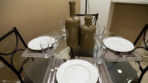 A dining table set with plates, cutlery, and glasses, surrounded by chairs. - Executive Suites at The Bromptons (Kingston)