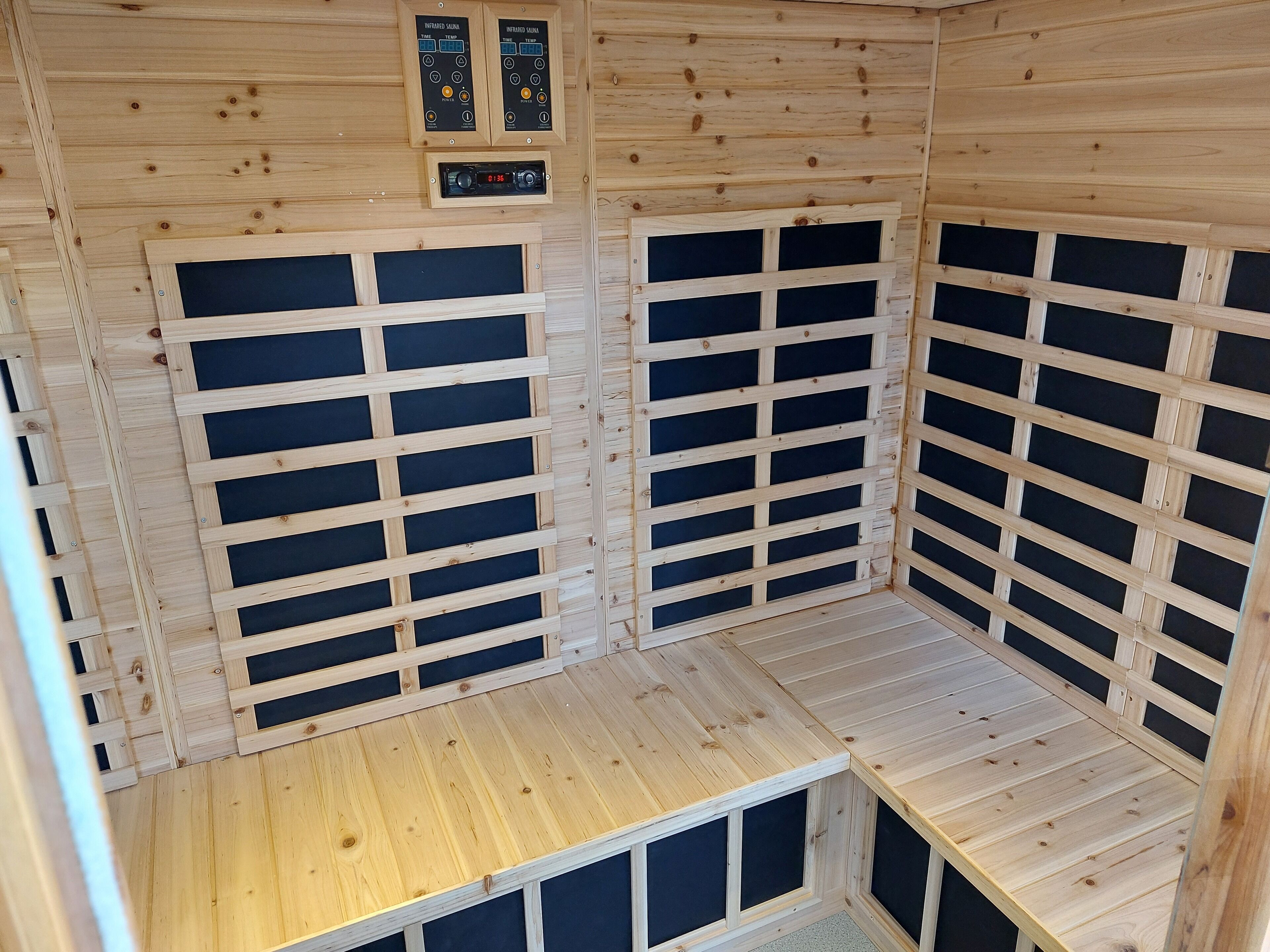 A wooden sauna room with a slatted ceiling, a control panel, and a bench.