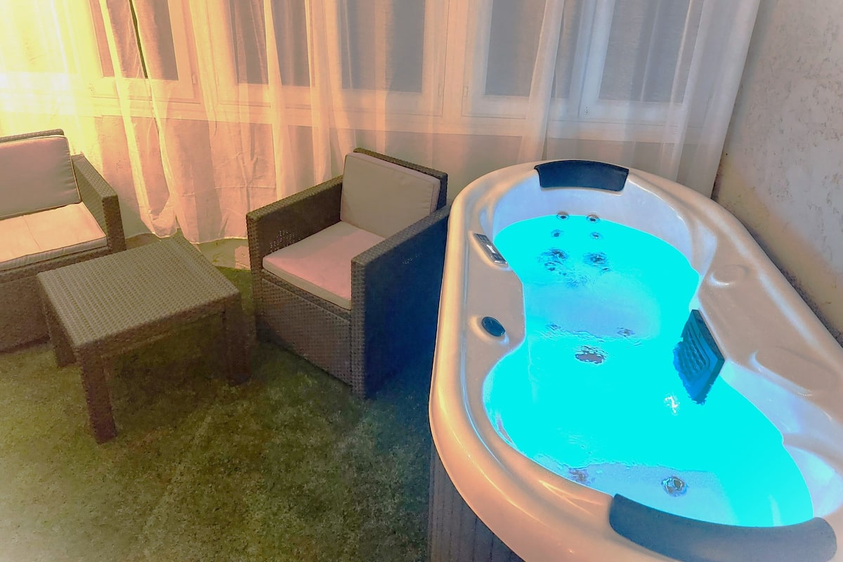 Un jacuzzi con interior azul, una silla de mimbre y una mesita.