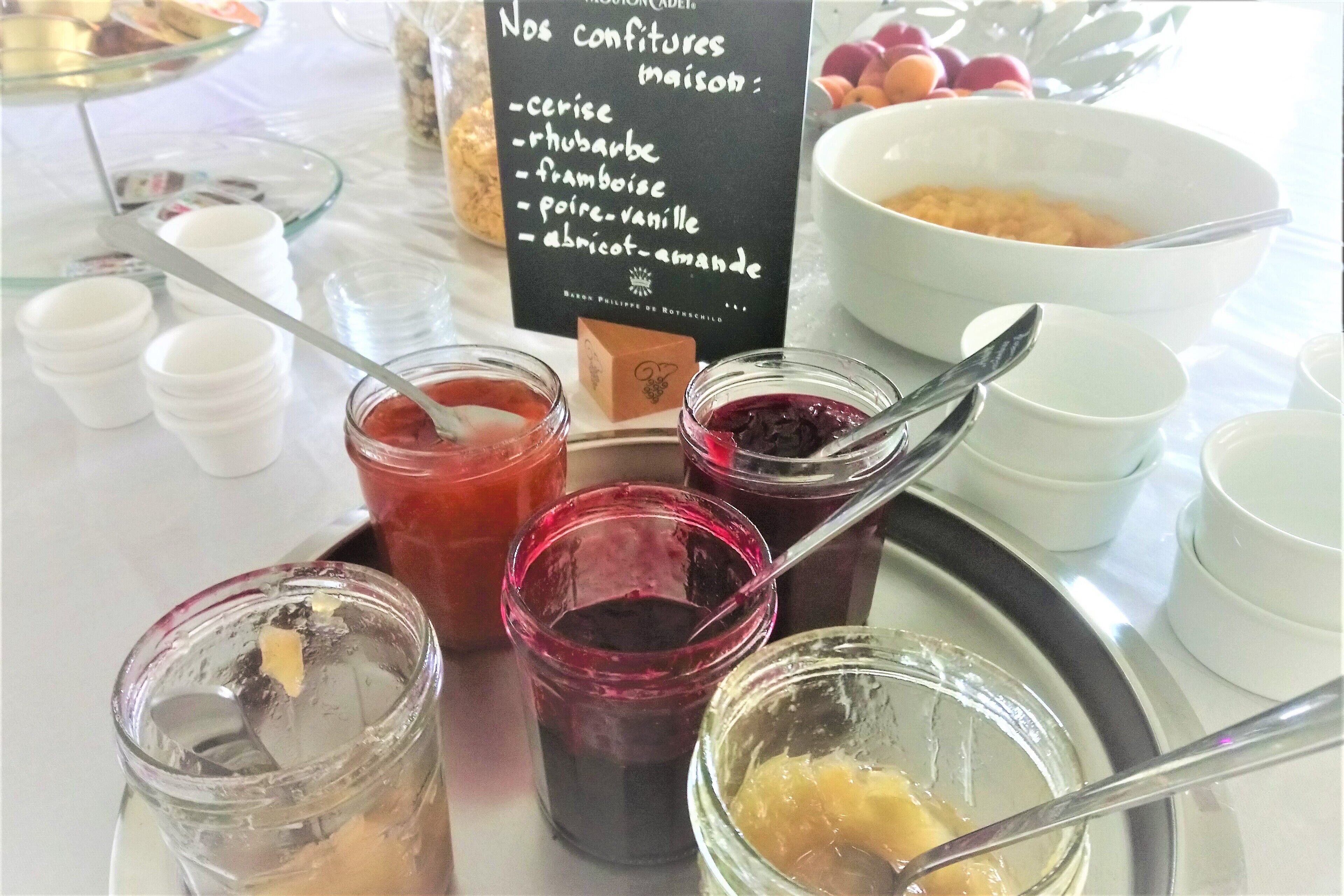 A table with various food items and condiments, including jars of preserves and a sign listing ingredients.