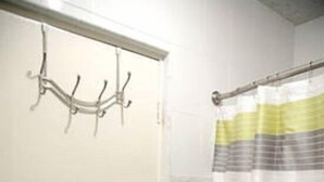 Un baño con cortina de ducha, dos toallas colgadas en un perchero y pared de azulejos.