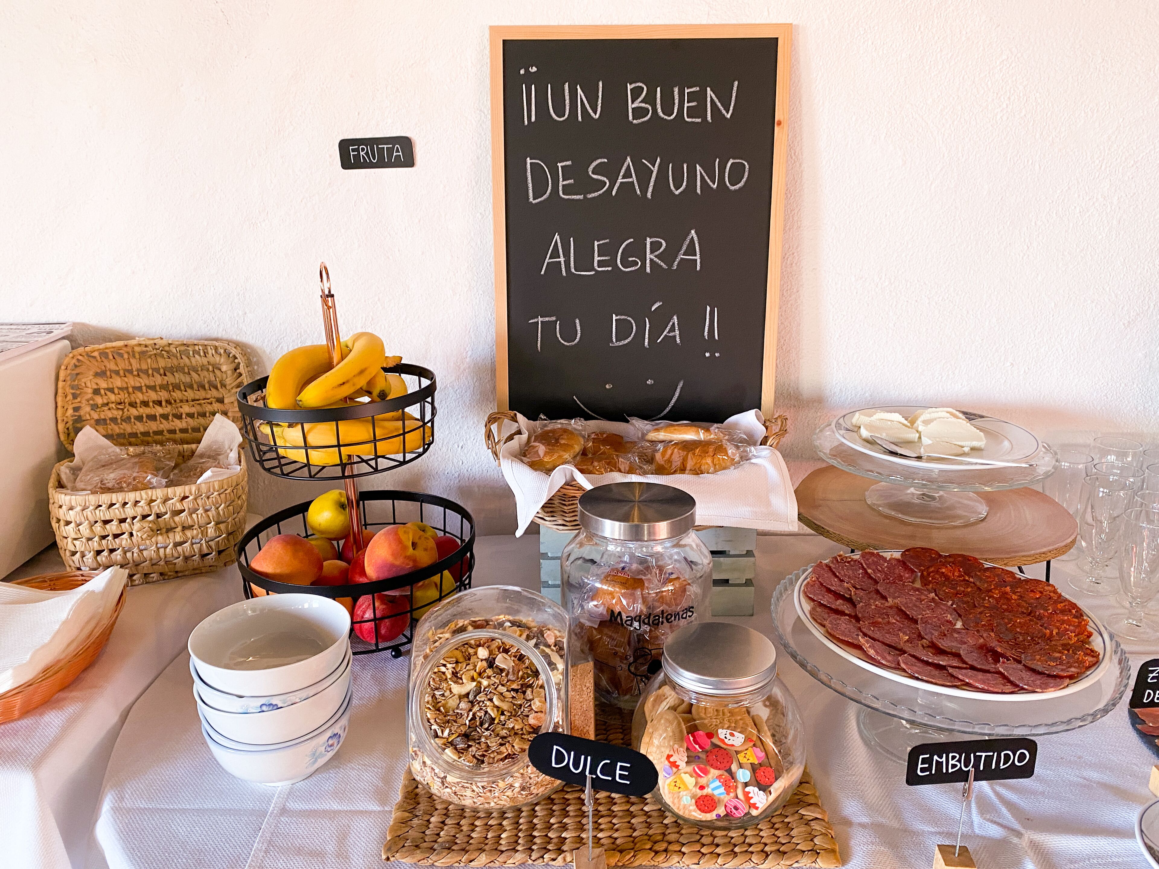 A breakfast buffet with various food items and a sign that says "Un buen desayuno te alegrar tu dia".