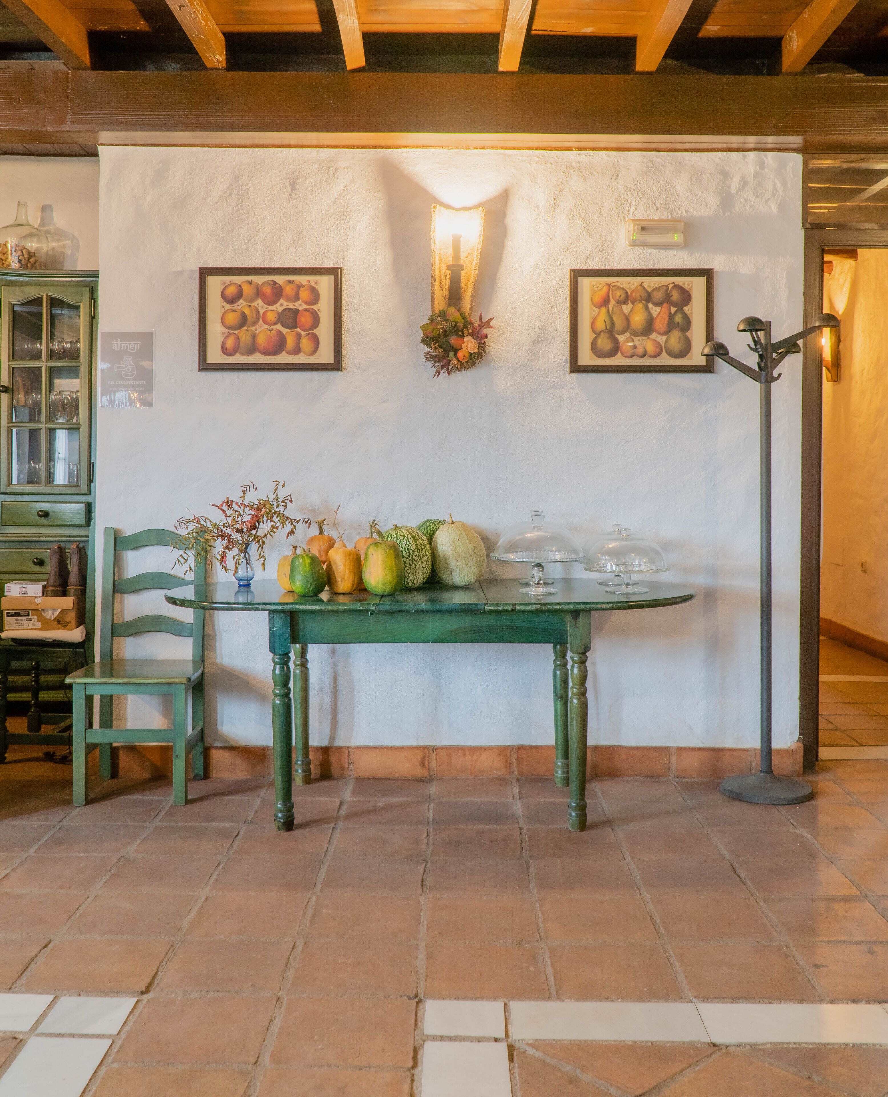 A dining area with a green table, chairs, and a wall-mounted light fixture.