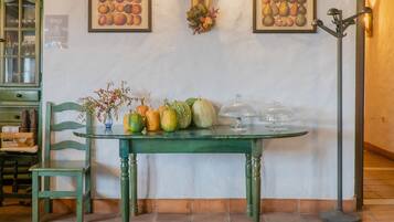 A dining area with a green table, chairs, and a wall-mounted light fixture.