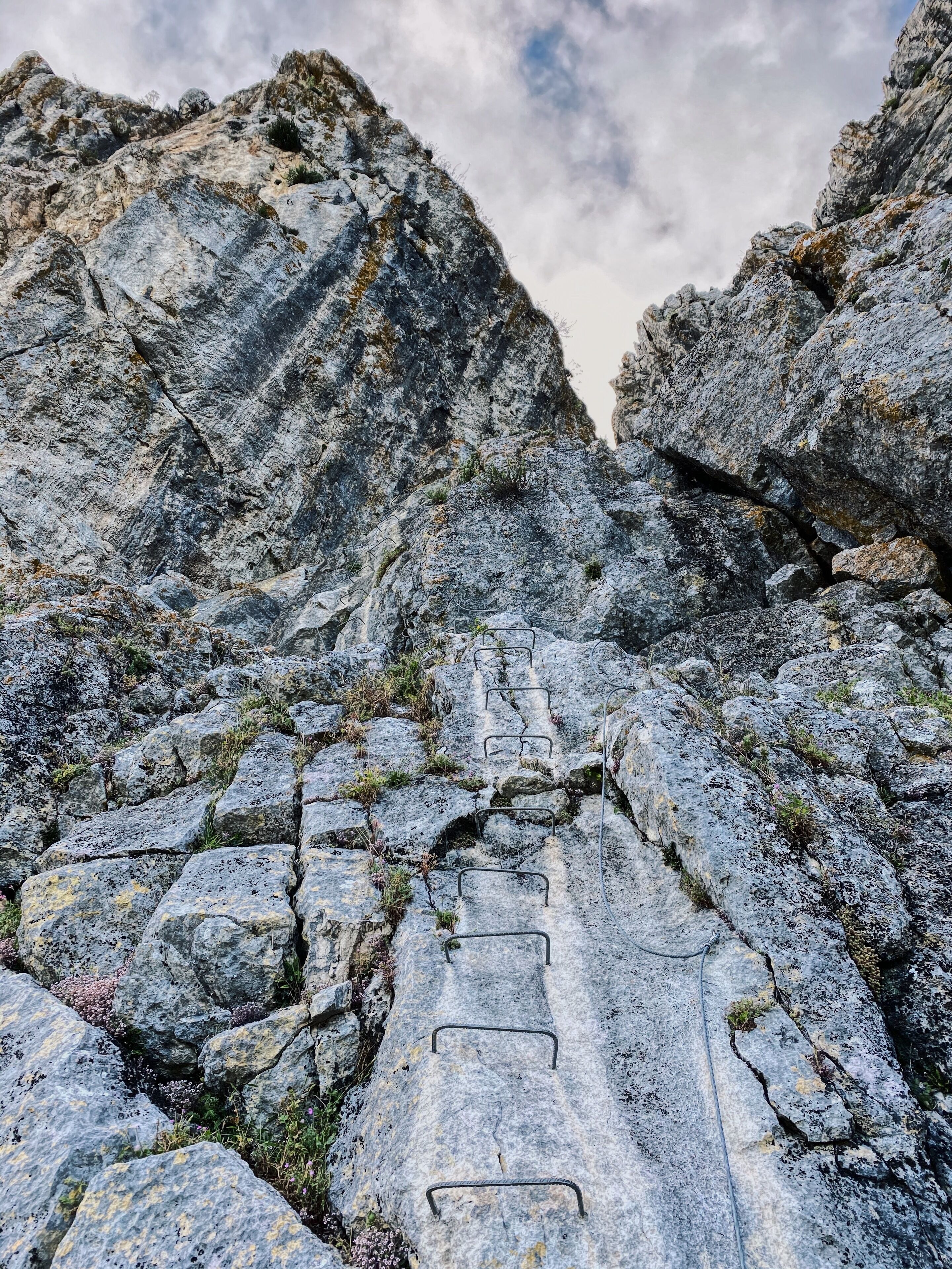 A rocky mountain path with metal handrails.