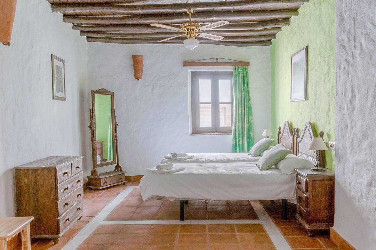 A bedroom with a bed, dresser, mirror, and a ceiling fan.