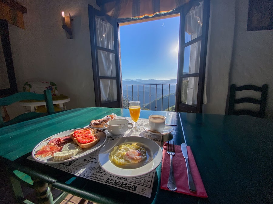 A table with breakfast items, a newspaper, and a glass of orange juice.