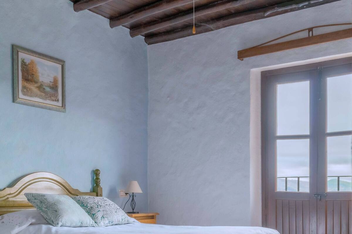 A bedroom with a bed, a ceiling fan, a window, and a door.