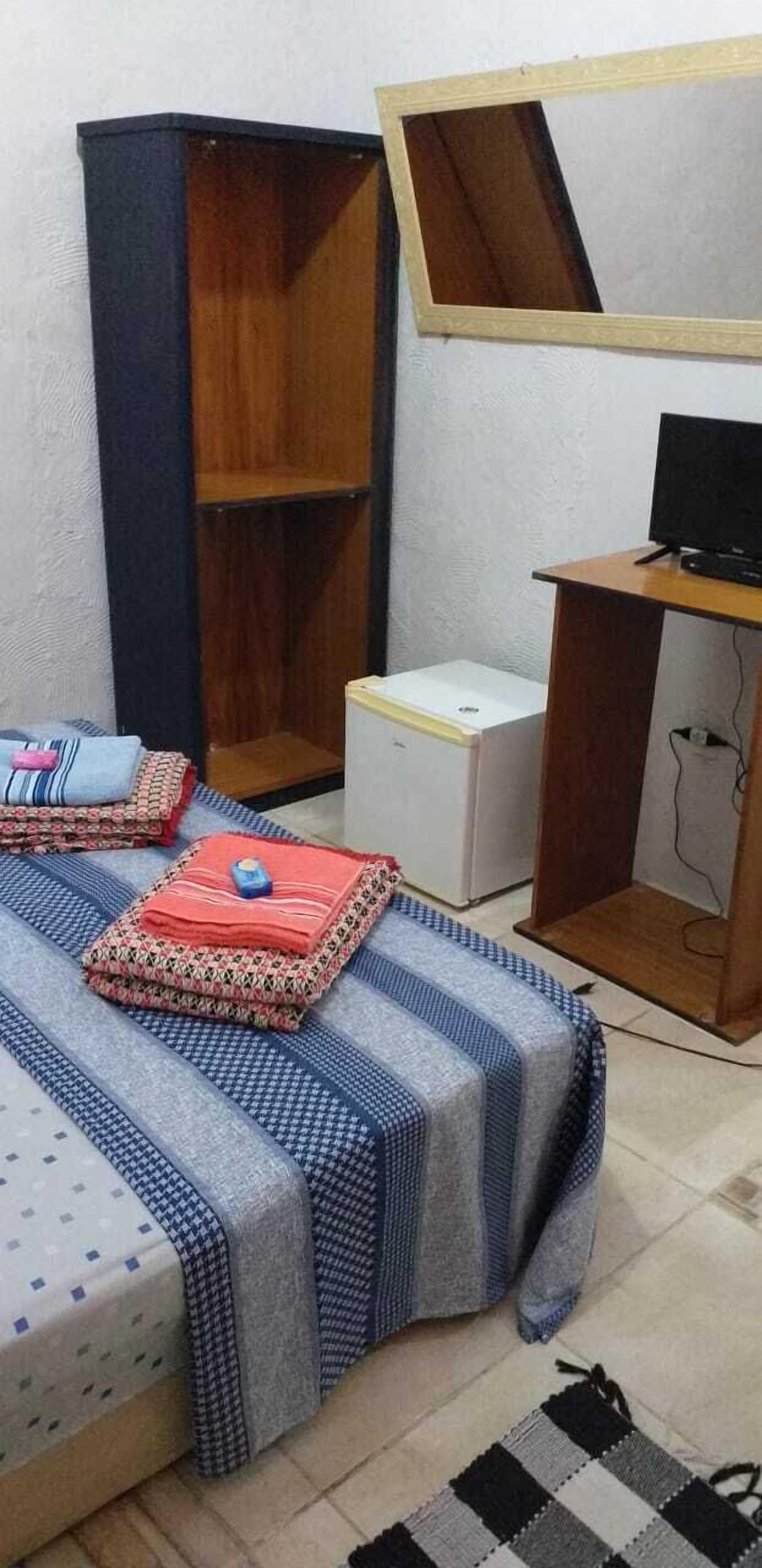 Un dormitorio con cama, escritorio, computadora y armario.