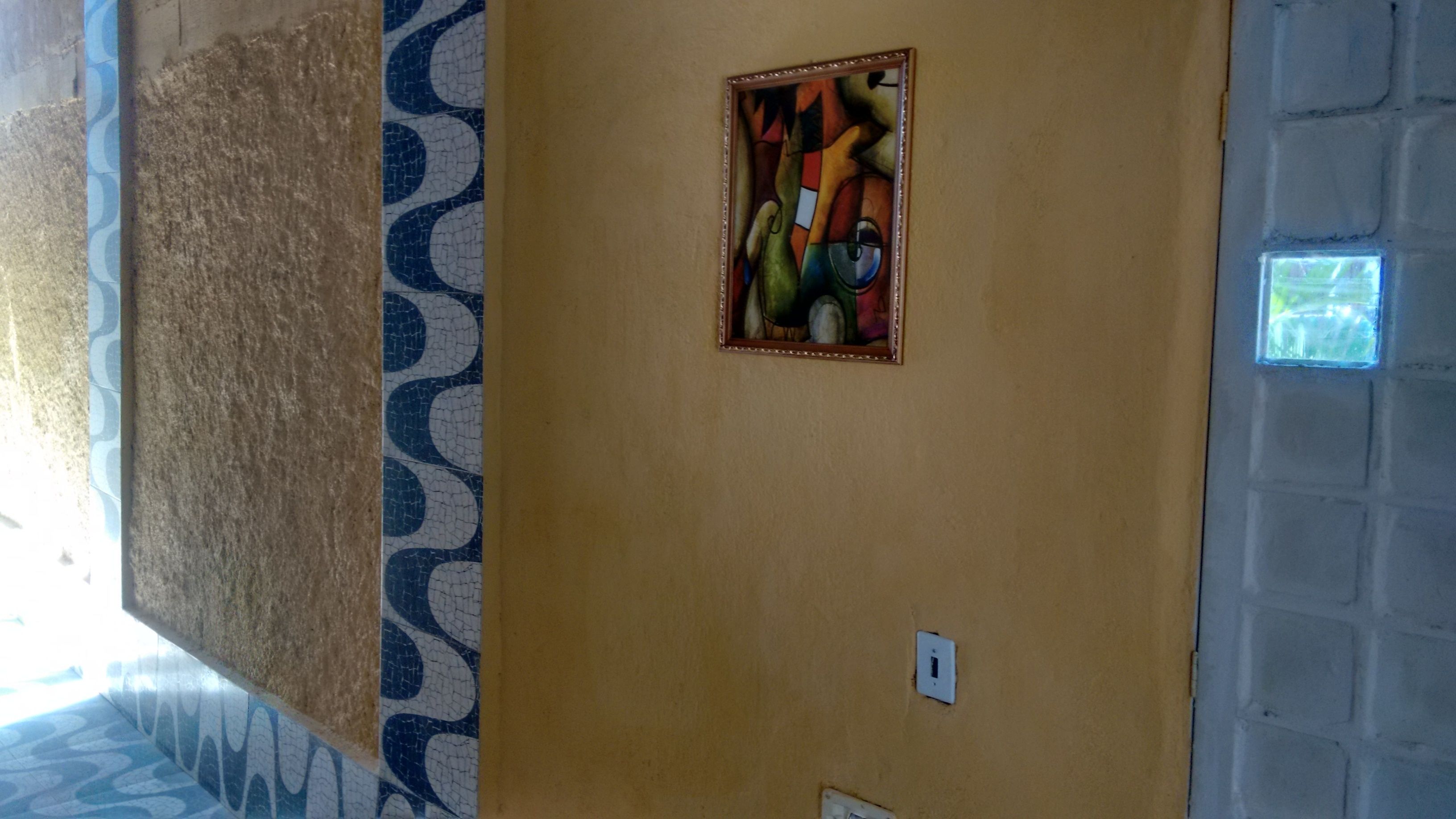 Un pasillo con piso estampado, una obra de arte enmarcada en la pared y un interruptor de luz.