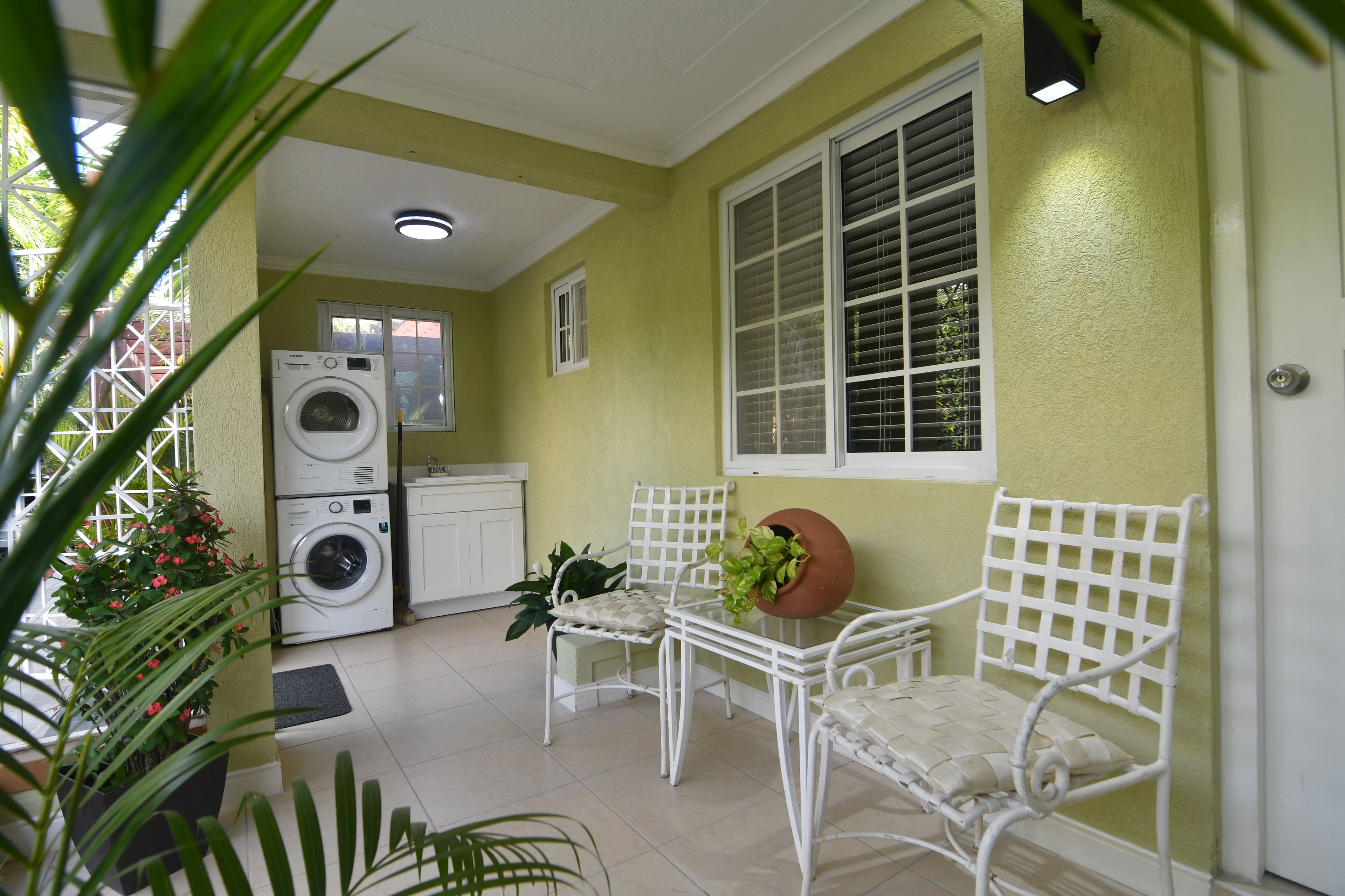 A laundry area with a washing machine and dryer, a small table with chairs, and a potted plant.