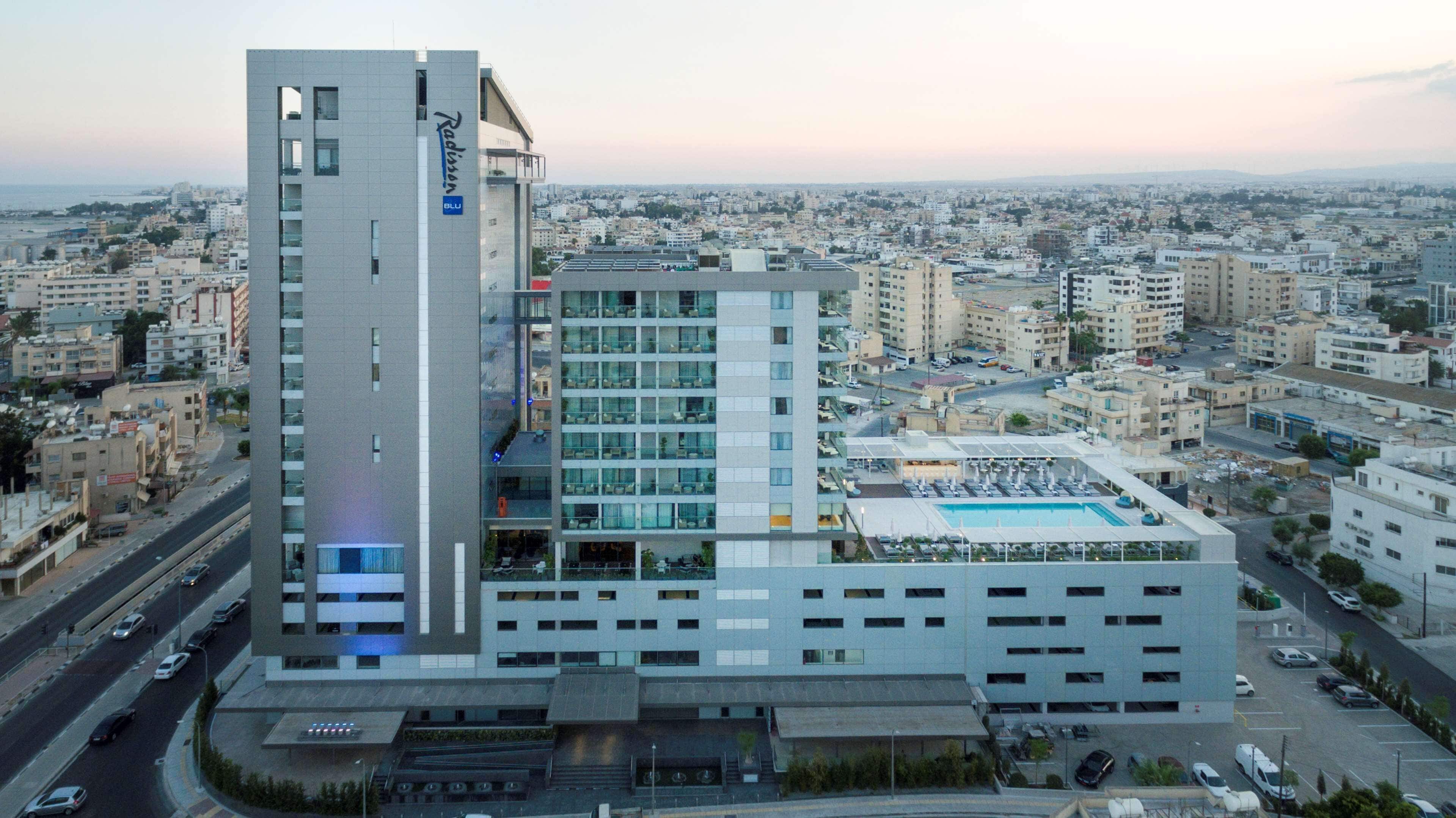 A modern hotel with a prominent tower, multiple floors, and a rooftop pool area.
