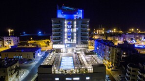 A multi-story hotel with a central atrium, multiple balconies, and a parking area.