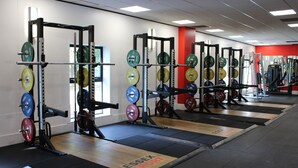 A gym with multiple weightlifting stations, each equipped with barbells and weight plates.