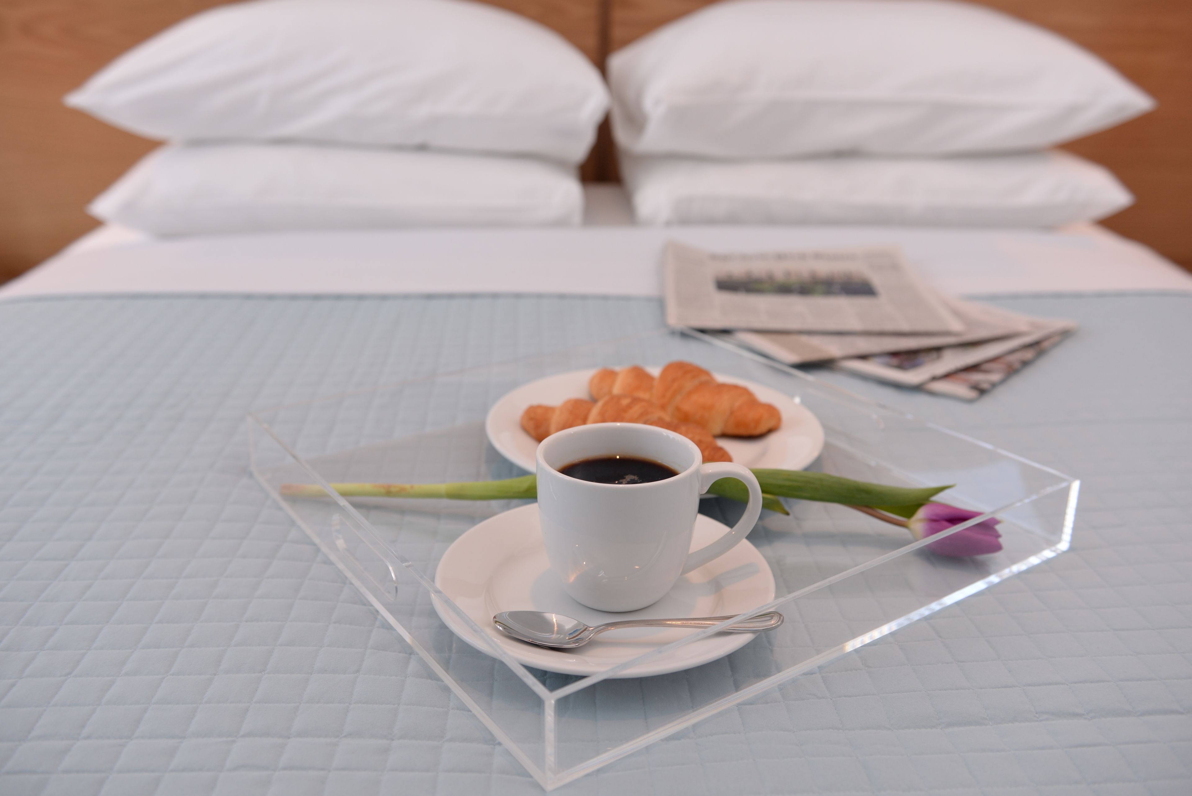 A neatly made bed with white pillows and a quilted blue bedspread.