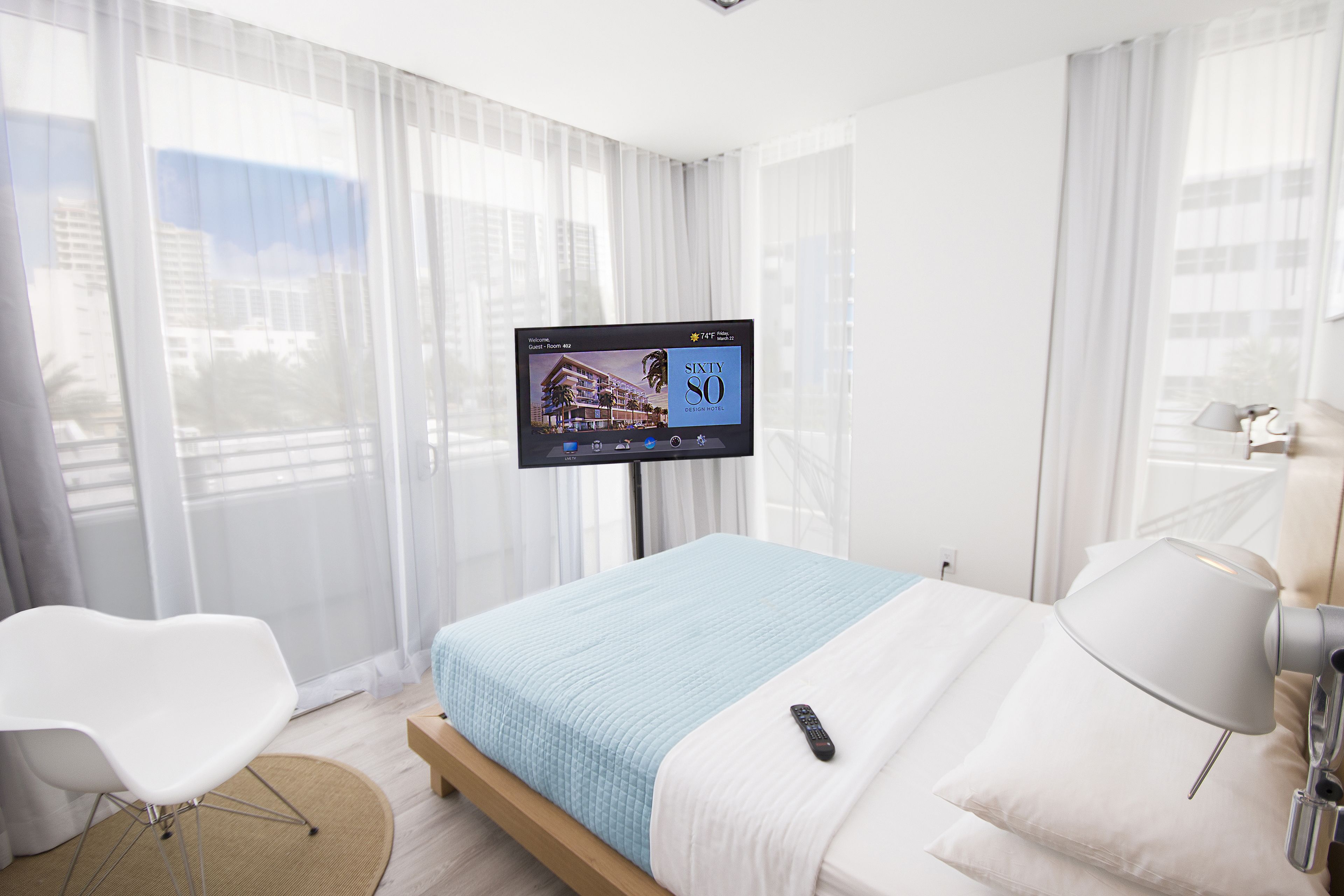 Ein Hotelzimmer mit einem Bett, einem an der Wand montierten Fernseher, einem Sessel und einer Lampe.