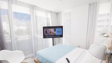 Ein Hotelzimmer mit einem Bett, einem an der Wand montierten Fernseher, einem Sessel und einer Lampe.