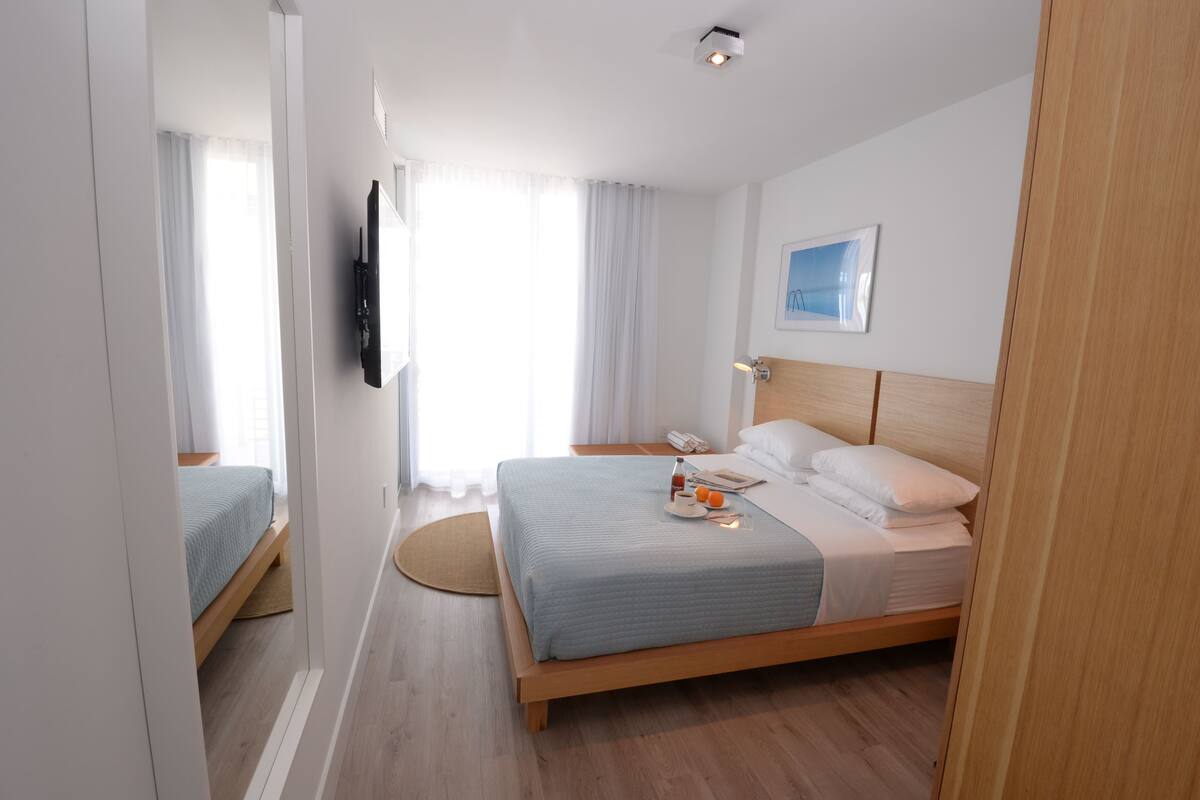 Habitación de hotel moderna con una cama grande, un televisor de pantalla plana y vista a la ciudad.