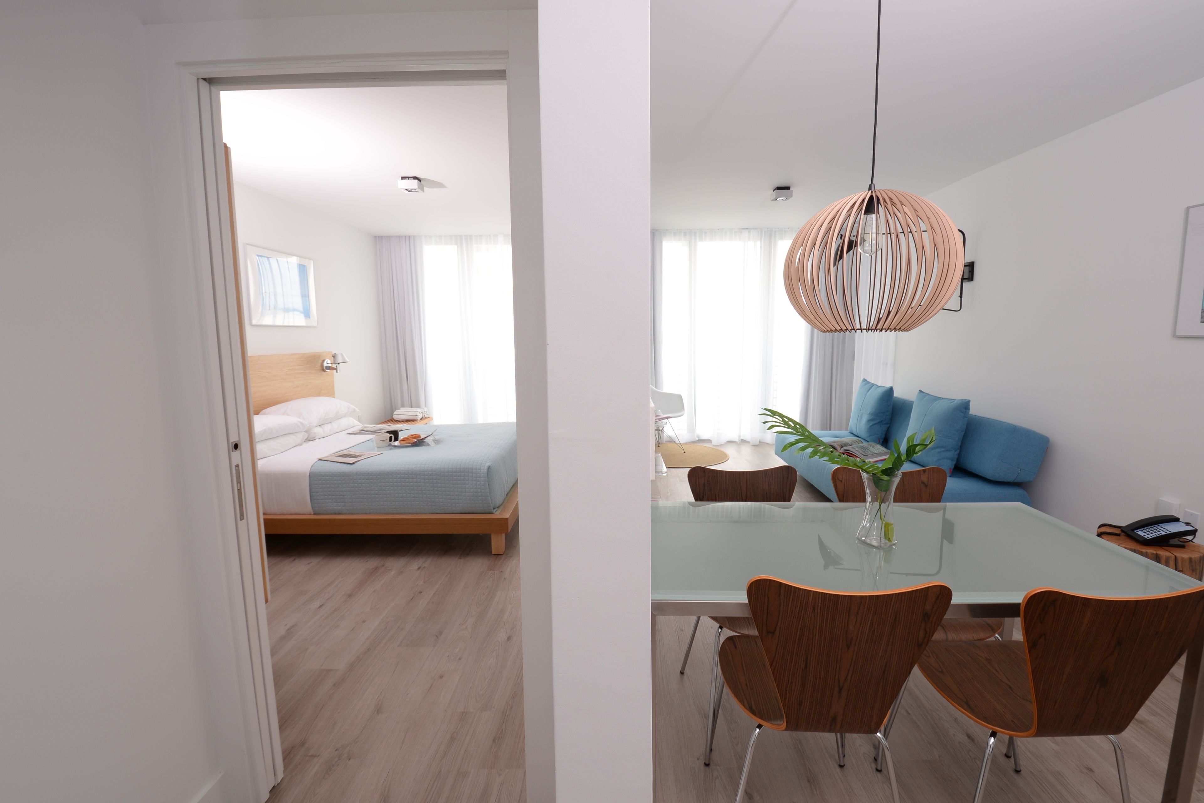 Een moderne hotelkamer met een bed, een zithoek met een glazen tafel en een woongedeelte met een bank.