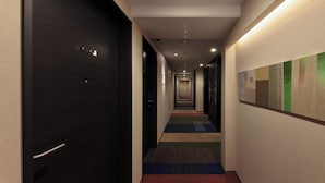 A hotel corridor with dark doors, a colorful carpet, and a wall-mounted abstract painting. - KUROMON Crystal Hotel (Osaka)