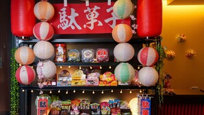 A store with shelves stocked with snacks and packaged goods, decorated with paper lanterns and a red banner. - KUROMON Crystal Hotel (Osaka)