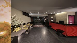 A hotel lobby with a reception desk, seating area, and a staircase leading to other floors. - KUROMON Crystal Hotel (Osaka)